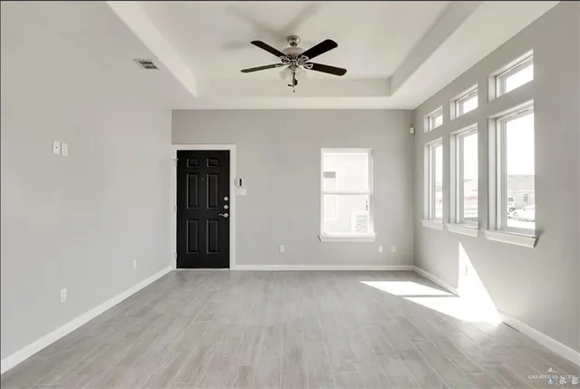 an empty room with windows and ceiling fan