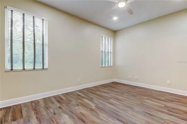 a view of empty room with wooden floor and fan