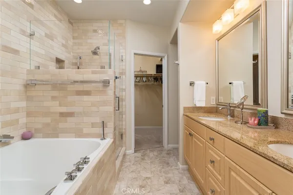 a bathroom with a granite countertop tub sink and mirror