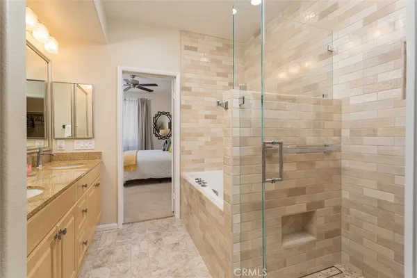 a en suite bathroom with a granite countertop sink a toilet a mirror and shower