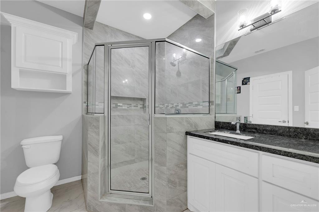 502 Oak Ridge Street Donna, TX 78537 - Photo 16 of 28 a bathroom with a granite countertop sink toilet and shower