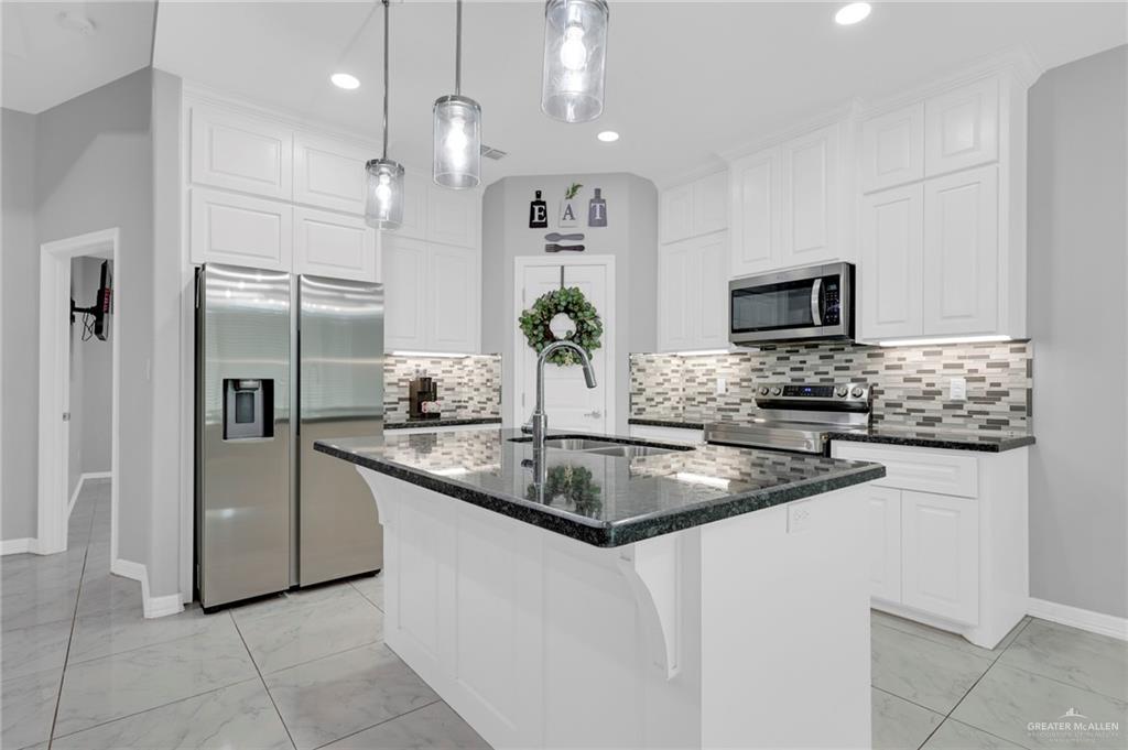 502 Oak Ridge Street Donna, TX 78537 - Photo 9 of 28 a kitchen with stainless steel appliances granite countertop a sink and a refrigerator