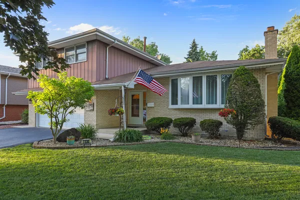 a front view of a house with a yard and potted plants