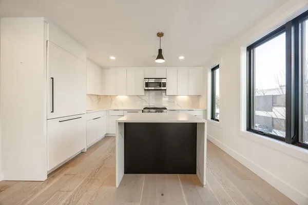 a kitchen with kitchen island white cabinets and refrigerator