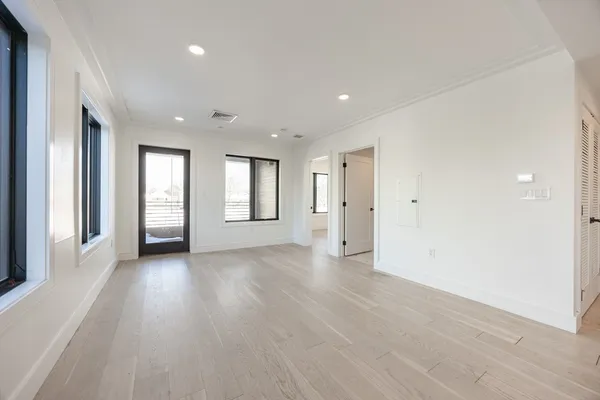 a view of an empty room with window and wooden floor