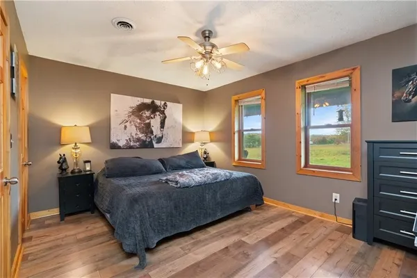 a bedroom with a bed and dresser with wooden floor