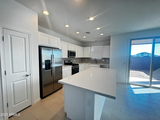 a large white kitchen with a large window and stainless steel appliances