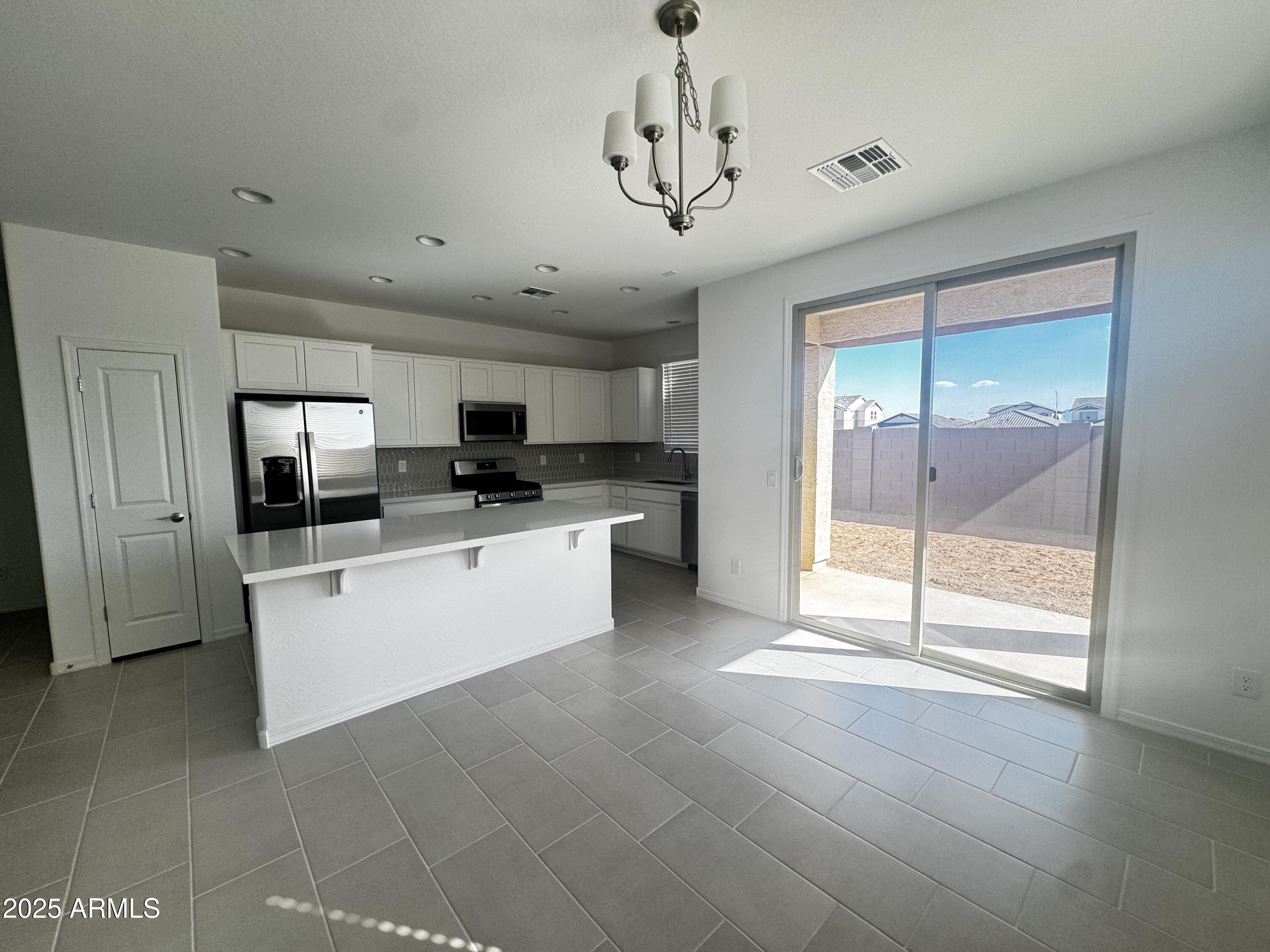 9957 West Mitchell Avenue Avondale, AZ 85392 - Photo 4 of 19 a large white kitchen with a large window and stainless steel appliances