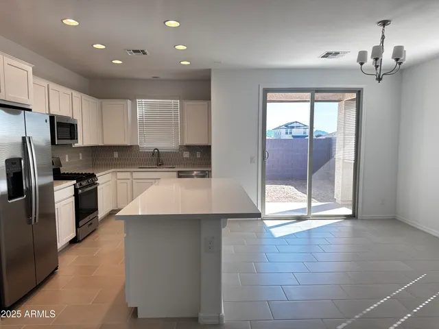 a kitchen with kitchen island granite countertop a stove a sink and a refrigerator with cabinets