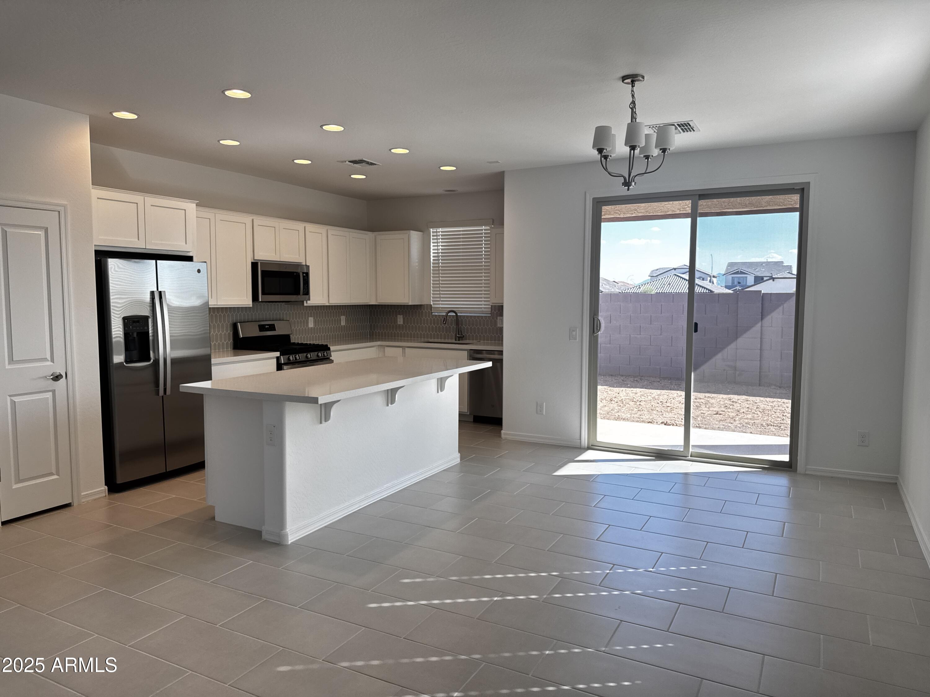 9957 West Mitchell Avenue Avondale, AZ 85392 - Photo 9 of 19 a kitchen with kitchen island granite countertop a stove a sink and a refrigerator with cabinets