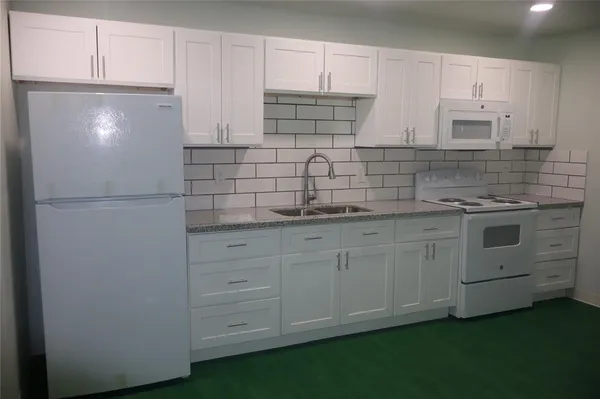 a kitchen with white cabinets and white appliances