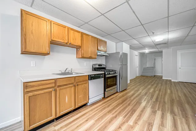 a kitchen with granite countertop wooden floors stainless steel appliances and sink