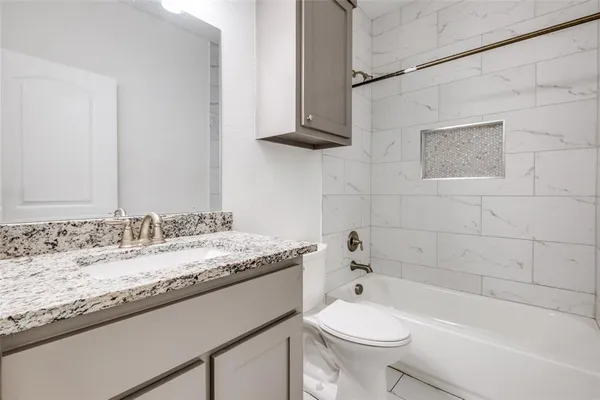 a bathroom with a granite countertop sink a toilet and bathtub