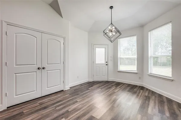 a view of an empty room with wooden floor and window