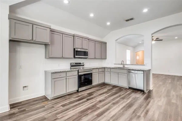 a large kitchen with cabinets wooden floor and stainless steel appliances