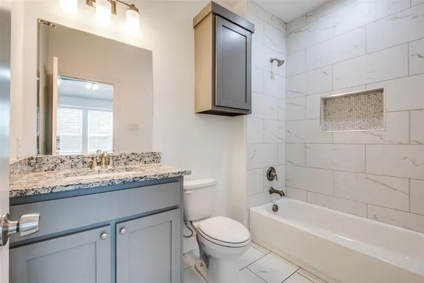 a bathroom with a granite countertop toilet sink and mirror
