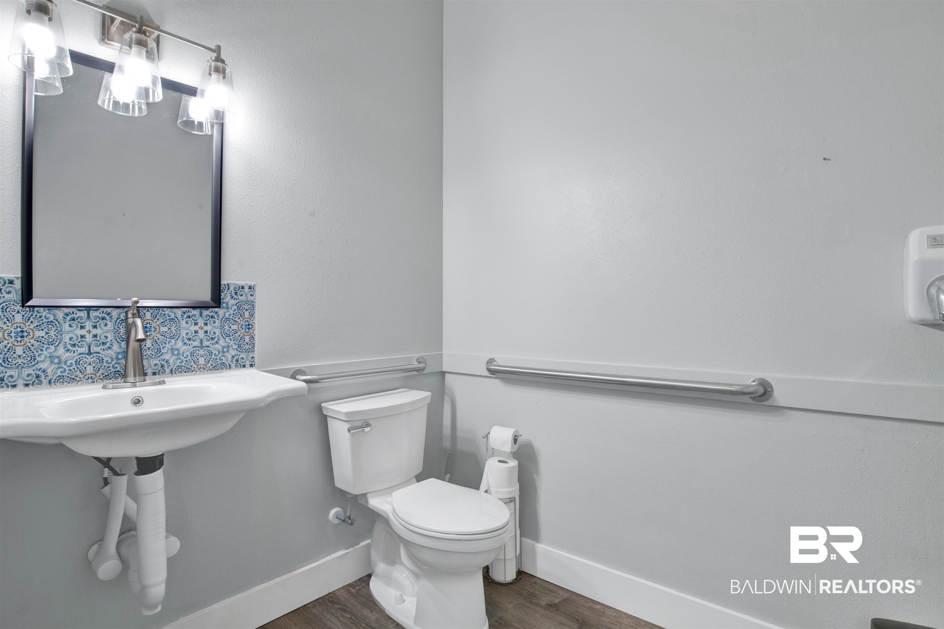 17714 Horseneck Road Bay Minette, AL 36507 - Photo 9 of 36 Bathroom featuring a pedestal sink with a decorative tile backsplash, a wall-mounted mirror, and a three-light vanity fixture