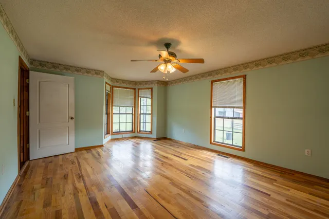 a view of an empty room with window and wooden floor