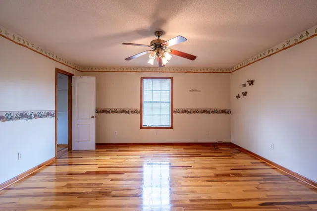 a view of empty room with wooden floor and fan