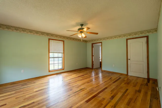 a view of an empty room with window and wooden floor