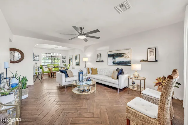 a living room with furniture kitchen view and a wooden floor