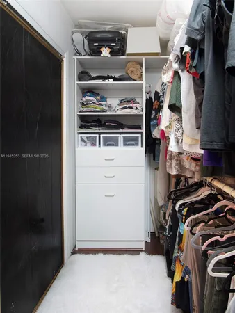 a view of walk in closet with clothes and shoes