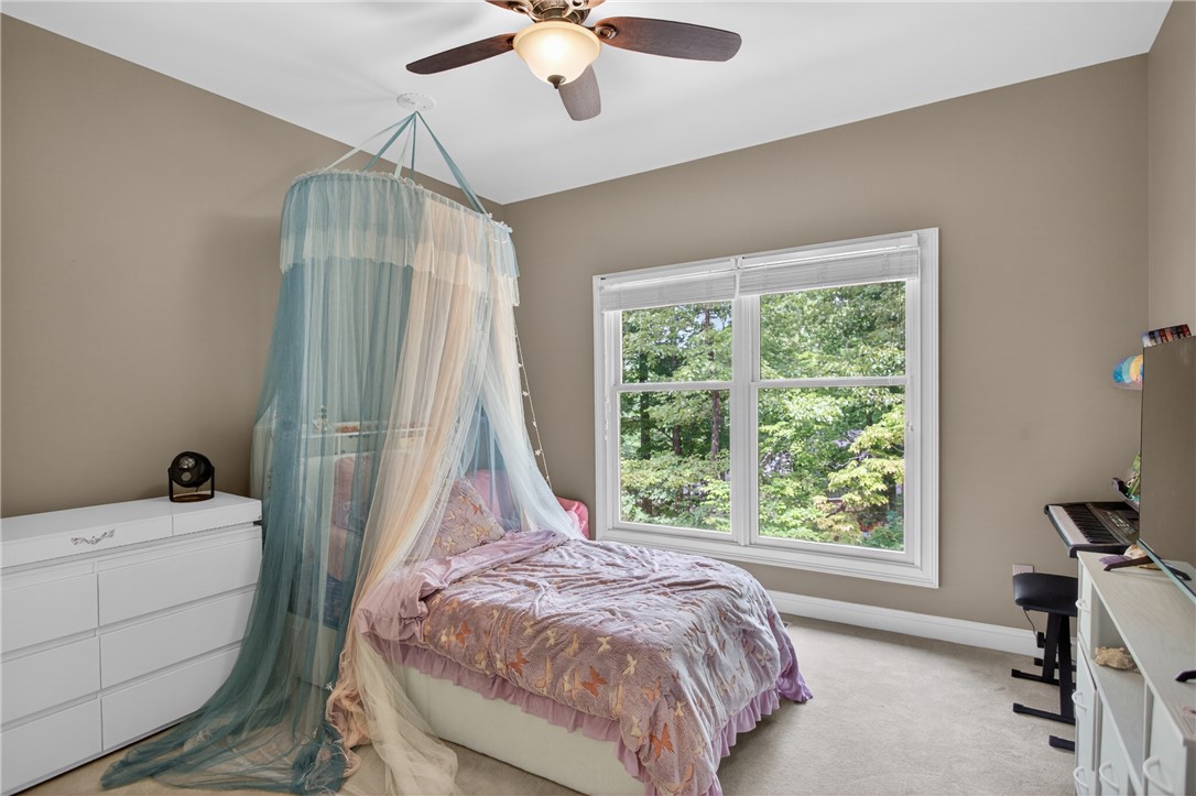 136 Loran Pointe Circle Seneca, SC 29672 - Photo 22 of 50 A well-lit bedroom with serene outdoor views features plush carpet and a practical ceiling fan.