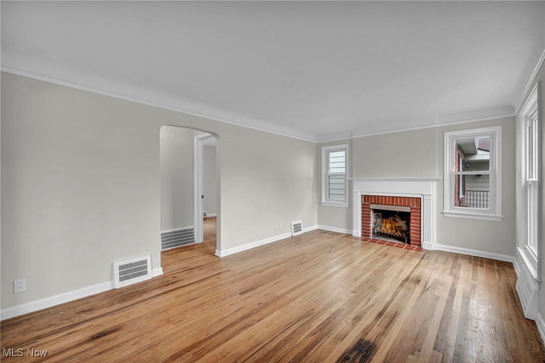 1176 Irene Road Lyndhurst, OH 44124 - Photo 5 of 36 living room featuring arched walkways, crown molding, a fireplace, and light hardwood flooring
