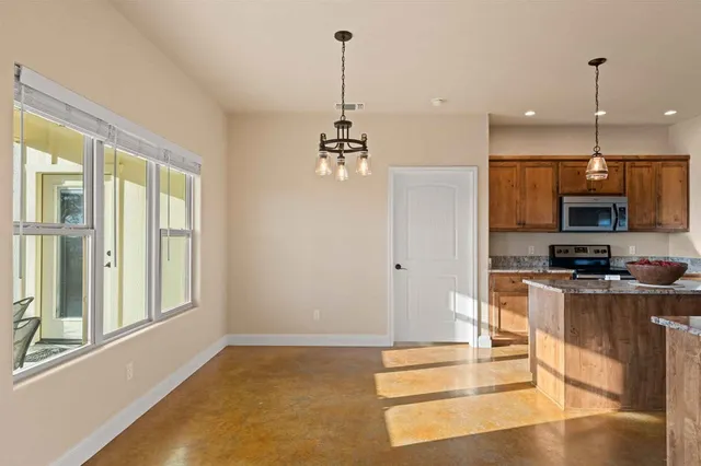 a kitchen with stainless steel appliances granite countertop a stove top oven a sink dishwasher a dining table and chairs