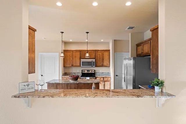 a kitchen with stainless steel appliances granite countertop a refrigerator a stove and a sink with granite countertops