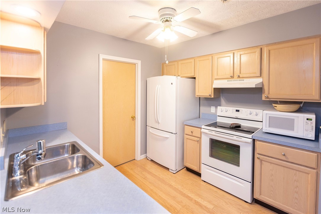 19510 Lorain Road, Unit 101 Cleveland, OH 44126 - Photo 9 of 24 Kitchen featuring white appliances, light wood-type flooring, light brown cabinets, sink, and ceiling fan