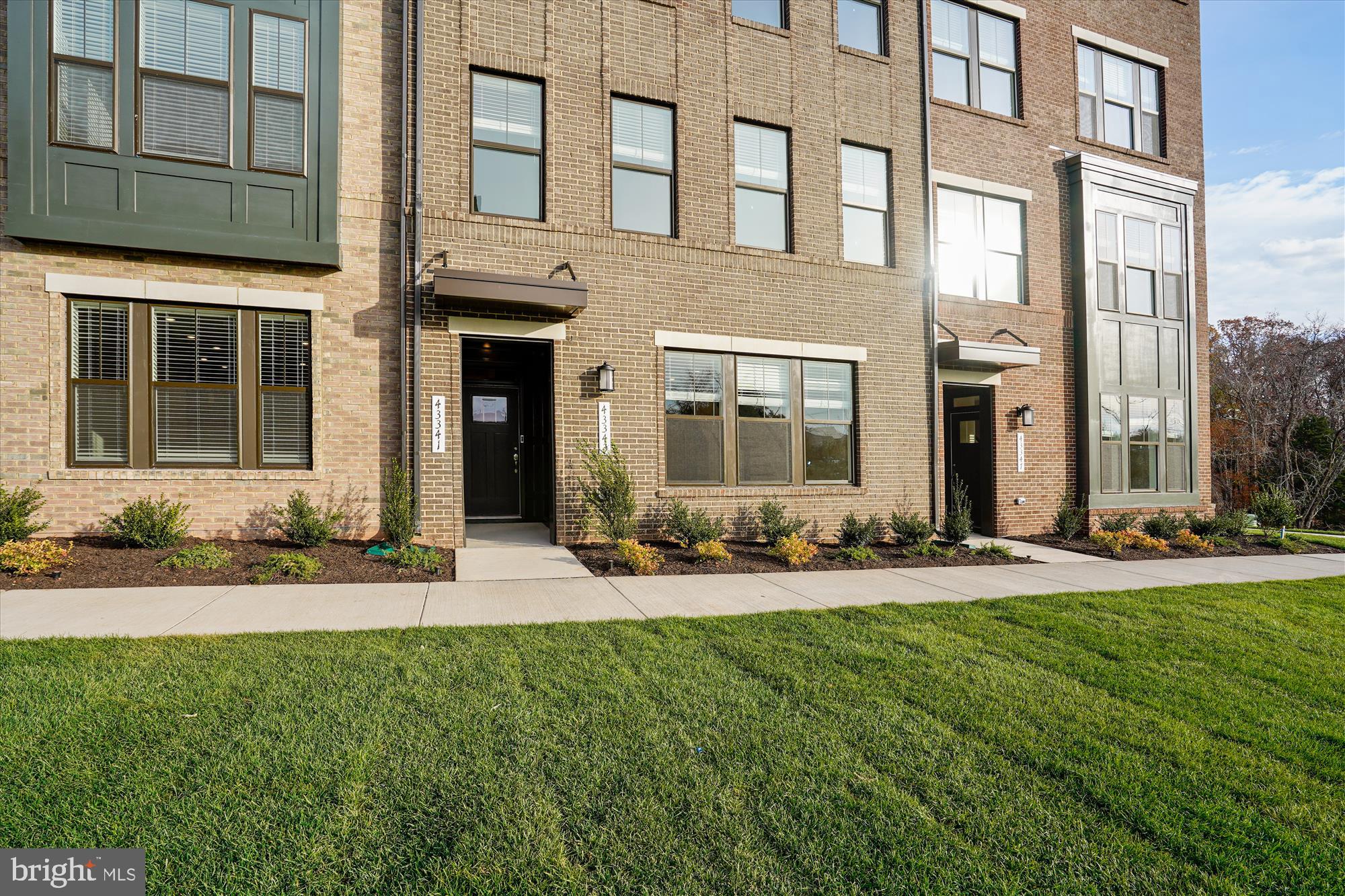 front view of a brick house with a yard and large trees