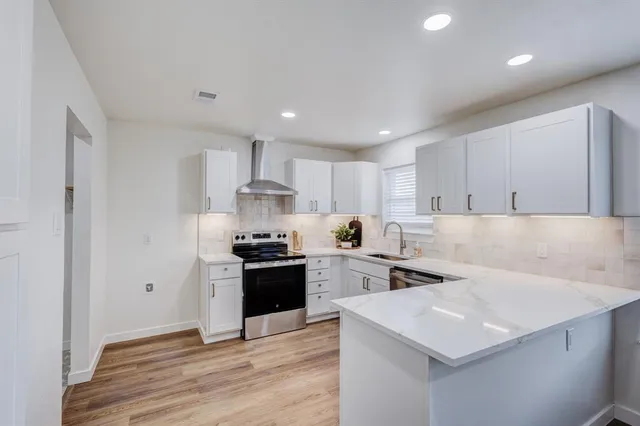 a kitchen with stainless steel appliances a stove top oven a sink a refrigerator and white cabinets