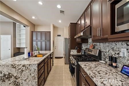 39366 11th Street West Palmdale, CA 93551 - Photo 14 of 15 a kitchen with stainless steel appliances kitchen island granite countertop a stove refrigerator and cabinets