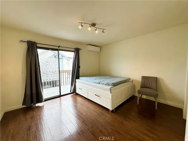 a spacious bedroom with a bed and wooden floor