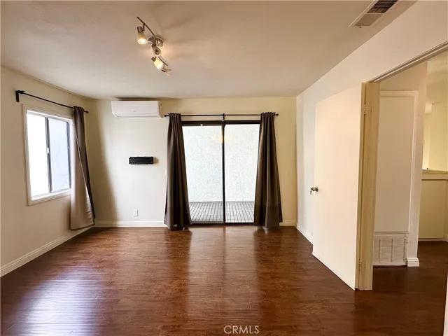 a view of an empty room with window and wooden floor