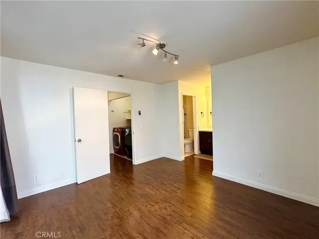 a view of an empty room with wooden floor and a ceiling fan
