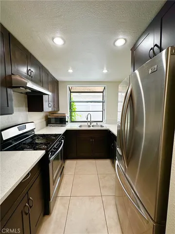 a kitchen with granite countertop a refrigerator a sink a stove and cabinets