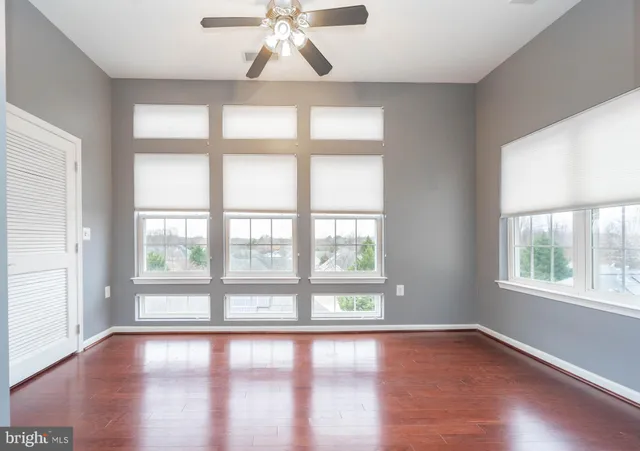 an empty room with wooden floor and windows