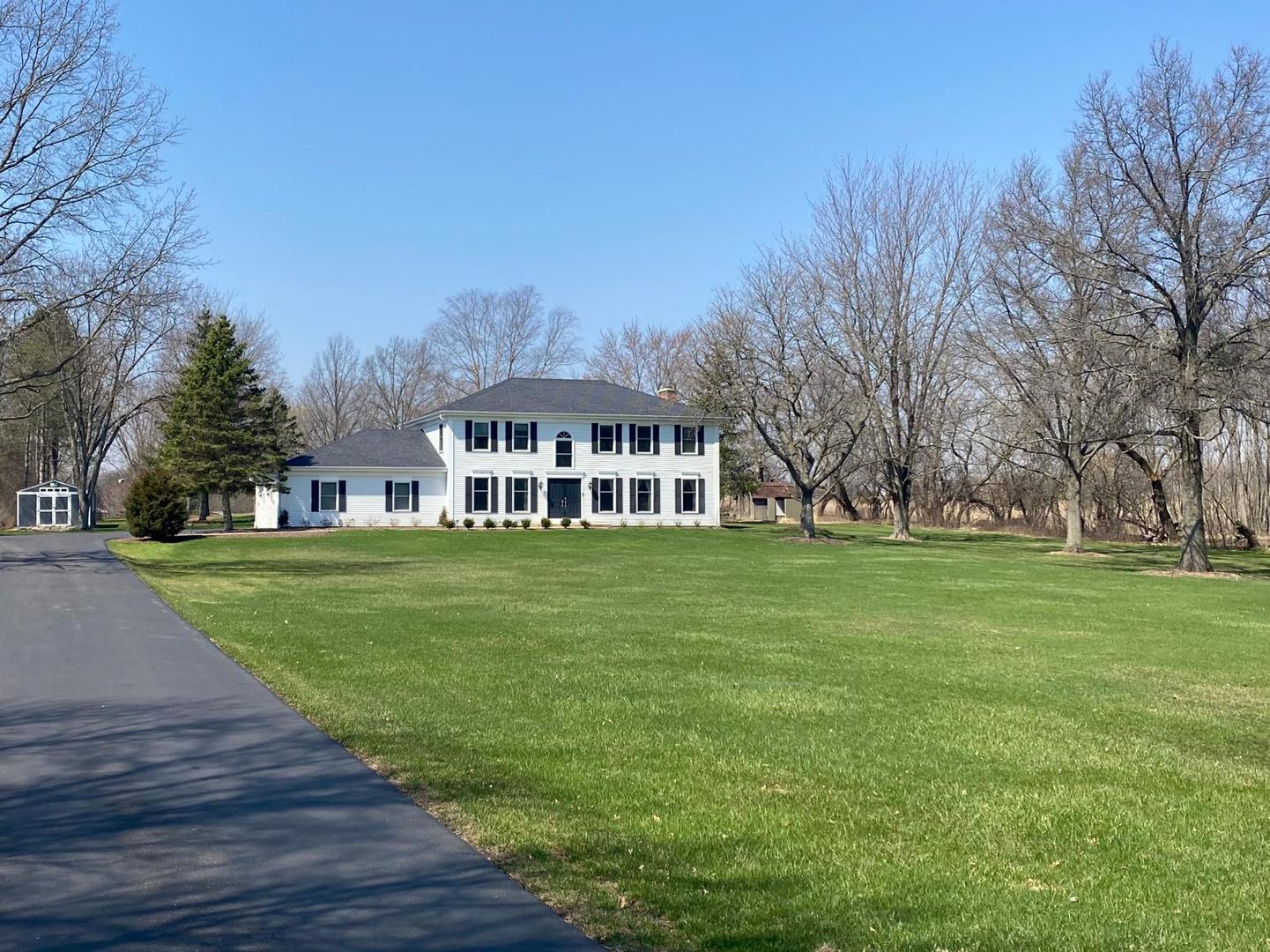 a view of house in front of a big yard with large trees