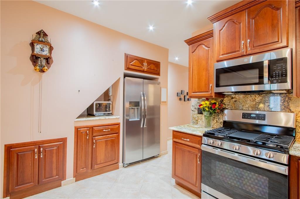 136 Bay Ridge Avenue Brooklyn, NY 11220 - Photo 25 of 48 a kitchen with stainless steel appliances granite countertop a refrigerator a stove and a sink with wooden cabinets
