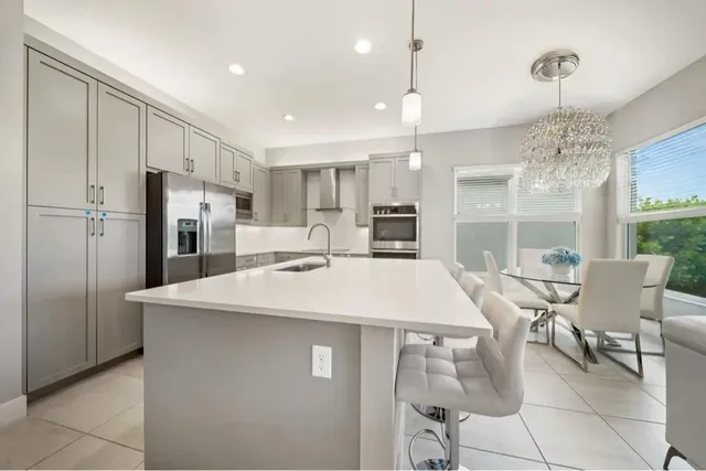 a kitchen with stainless steel appliances kitchen island a table chairs and chandelier