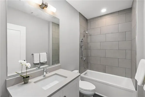 a bathroom with a bathtub shower sink vanity mirror and toilet
