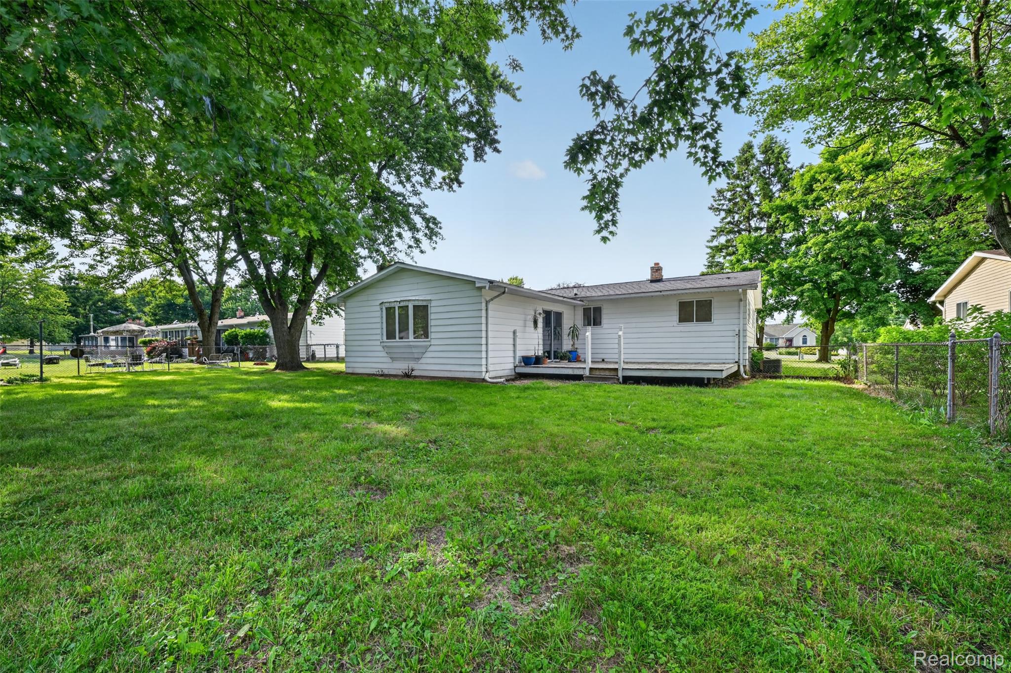 5457 Reid Road Swartz Creek, MI 48473 - Photo 44 of 51 Expansive rear yard featuring a large grass area, mature trees providing natural shade, a white-sided exterior, a rear deck, and a bay window