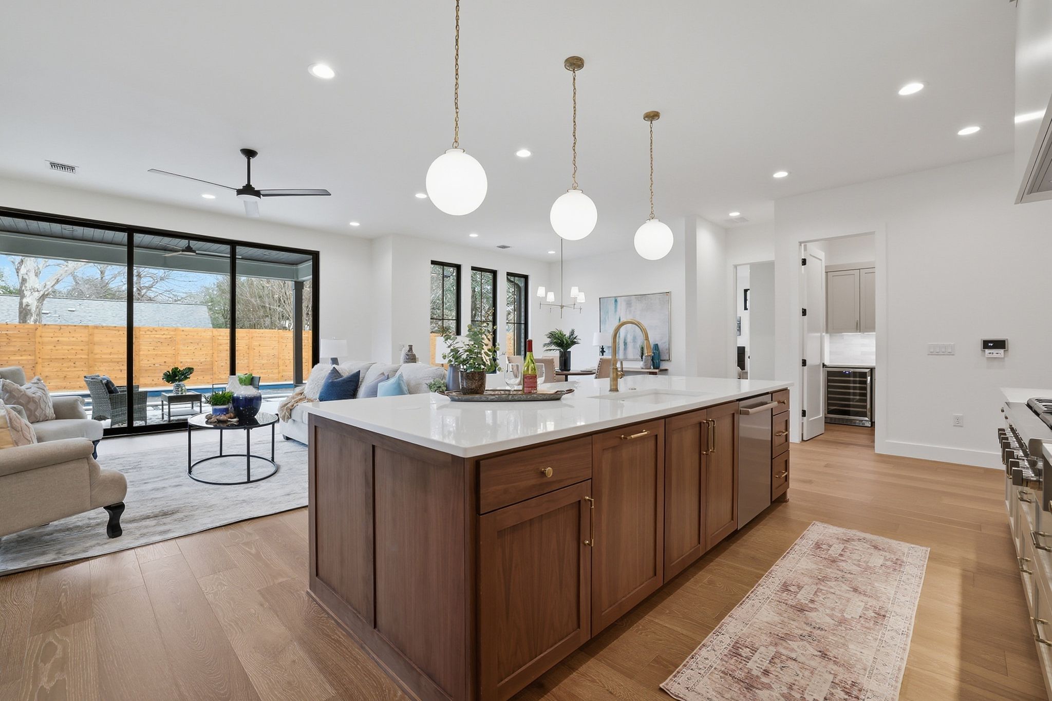 6611 Lexington Road Austin, TX 78757 - Photo 11 of 37 Open-concept living space featuring wood-finish flooring, a kitchen island with stone countertop, built-in stainless steel appliances, and large sliding glass doors opening to the exterior