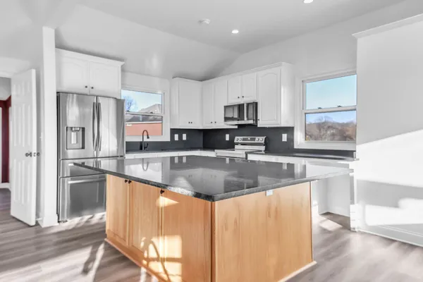 a view of a kitchen with kitchen island wooden floor and stainless steel appliances