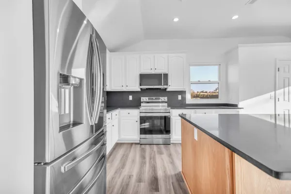 a kitchen with stainless steel appliances granite countertop a sink a stove and a wooden floors