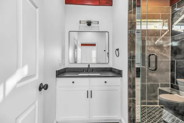 a bathroom with a granite countertop shower a sink and a mirror