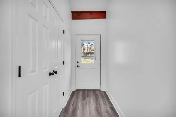 a view of an empty room with wooden floor and a window