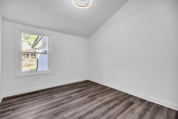 a view of empty room with wooden floor and window